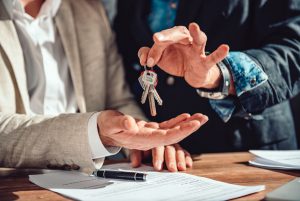 Real estate agent passing apartment keys to a client in the office